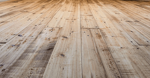 Wooden floorboards, light brown with knots and grain detail, in perspective.