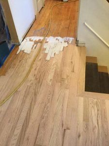 Wood floor installation in progress; planks laid on stairs and extending into a room.