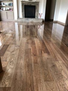 Shiny wooden floor reflecting the fireplace and room's interior.