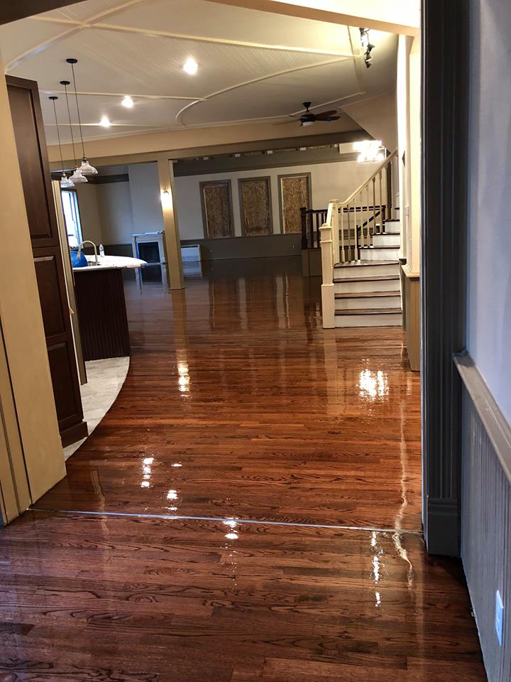 Shiny hardwood floors lead to a large, open-concept living area with a staircase and kitchen visible.